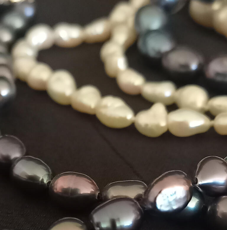 Several freshwater pearl necklaces in various colours knotted using traditional threading technique.